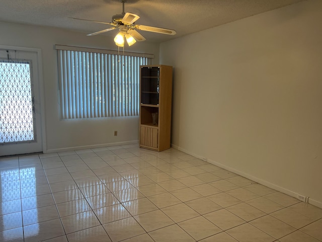 tiled spare room featuring ceiling fan, a textured ceiling, and a wealth of natural light