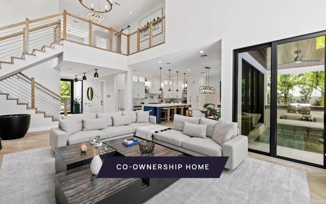 living room featuring an inviting chandelier, light parquet flooring, and a towering ceiling