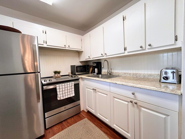 kitchen featuring stainless steel appliances, sink, light stone counters, white cabinetry, and dark wood-type flooring