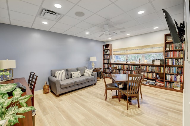 living room featuring light hardwood / wood-style flooring, a paneled ceiling, and ceiling fan