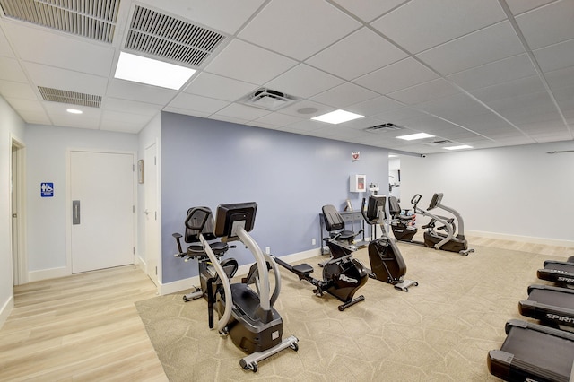 exercise room featuring light hardwood / wood-style flooring and a drop ceiling