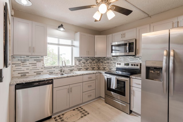 kitchen with sink, decorative backsplash, ceiling fan, and stainless steel appliances