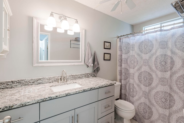 bathroom featuring a textured ceiling, toilet, vanity, and ceiling fan