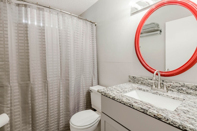 bathroom with toilet, vanity, and a textured ceiling