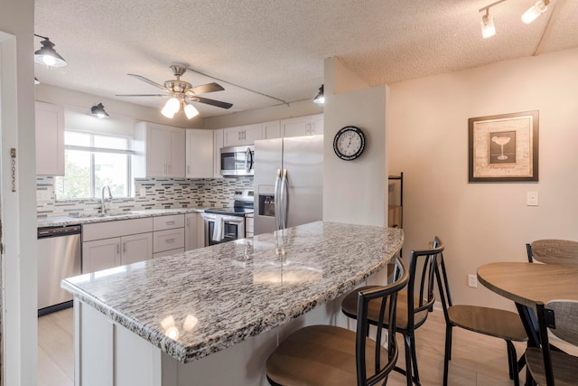 kitchen featuring decorative backsplash, appliances with stainless steel finishes, ceiling fan, and white cabinets