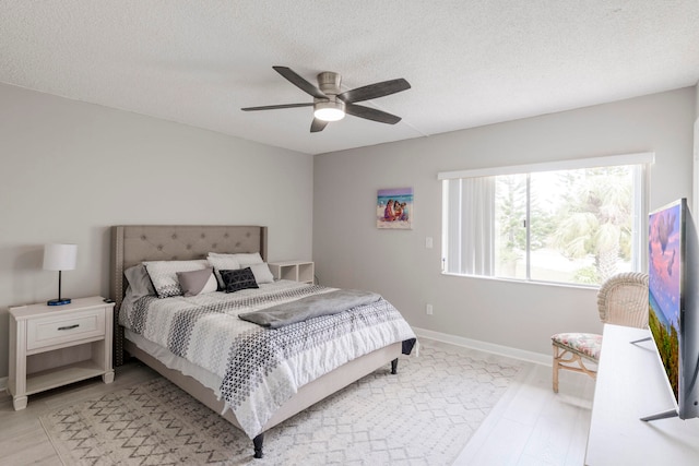 bedroom with light hardwood / wood-style flooring, a textured ceiling, and ceiling fan