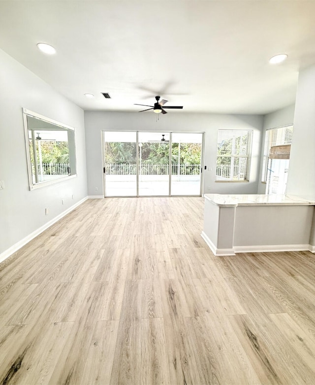 unfurnished living room featuring ceiling fan, light wood-type flooring, and a wealth of natural light