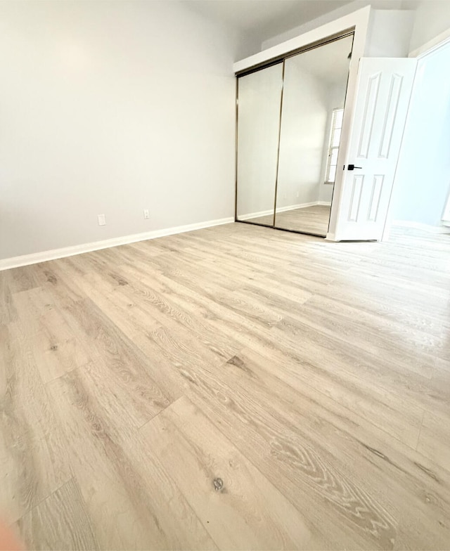 unfurnished bedroom featuring light wood-type flooring and a closet