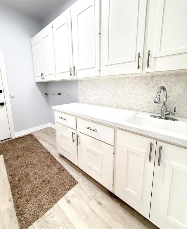 7504 SE Marsh Fern Ln, Hobe Sound, FL 33455 - laundry room featuring cabinet space, light wood-style flooring, washer hookup, and baseboards