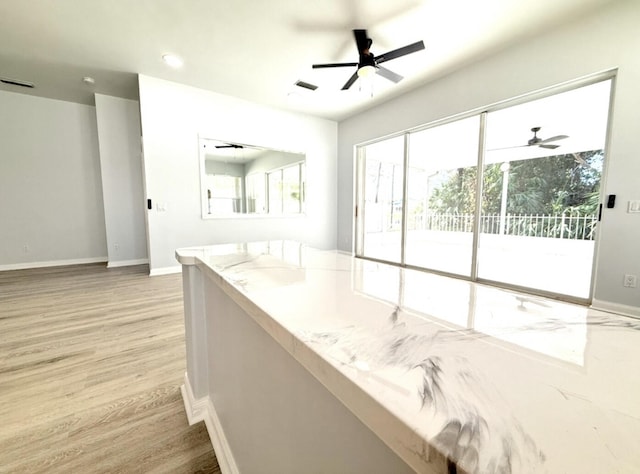 interior space with light stone counters, light hardwood / wood-style flooring, and ceiling fan