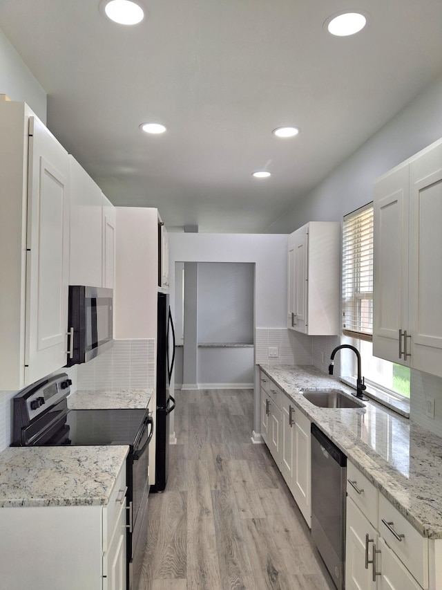 7504 SE Marsh Fern Ln, Hobe Sound, FL 33455 - kitchen with black appliances, light wood-style flooring, white cabinetry, and recessed lighting