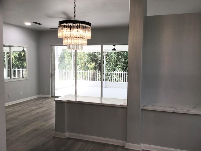 unfurnished dining area with dark wood-type flooring and a notable chandelier