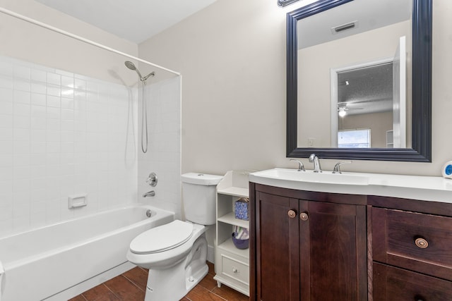 full bathroom featuring vanity, ceiling fan, wood-type flooring, toilet, and tiled shower / bath