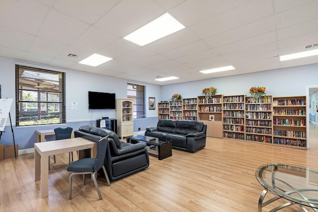 living room with a paneled ceiling and light hardwood / wood-style floors