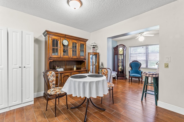 dining space featuring ceiling fan, dark wood-type flooring, and a textured ceiling