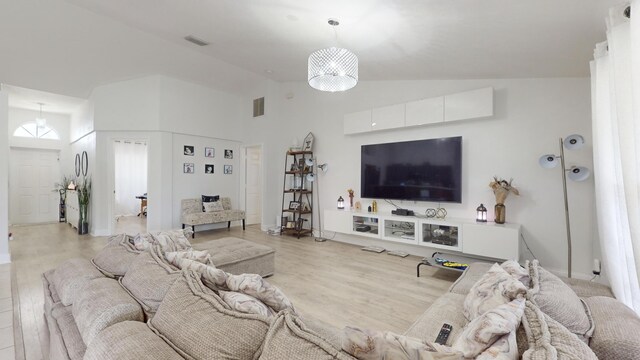 living room featuring high vaulted ceiling and light hardwood / wood-style flooring