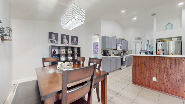 tiled dining area featuring high vaulted ceiling