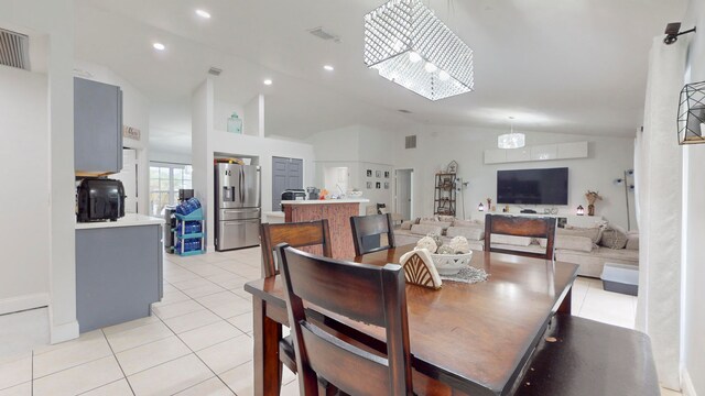 dining room with a notable chandelier, light tile patterned flooring, and high vaulted ceiling