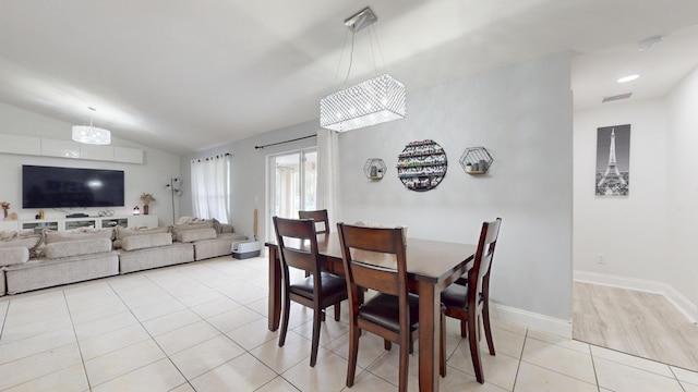 dining room featuring light tile patterned floors, vaulted ceiling, visible vents, and baseboards