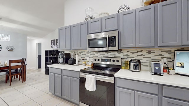 kitchen featuring stainless steel appliances, gray cabinets, light countertops, and decorative backsplash