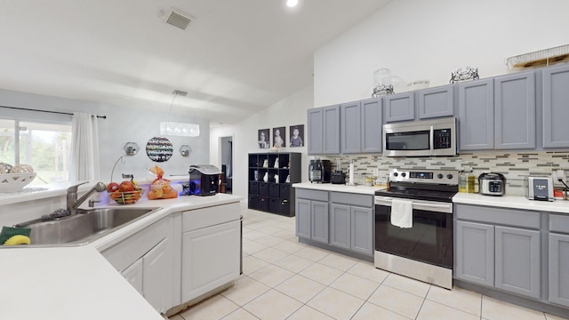 kitchen with stainless steel appliances, a sink, visible vents, light countertops, and pendant lighting