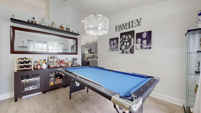 game room with bar, billiards, light wood-type flooring, and a high ceiling