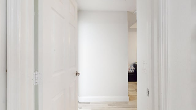 hall with light wood-style flooring and baseboards