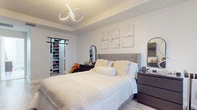 bedroom featuring hardwood / wood-style flooring, a raised ceiling, and a chandelier