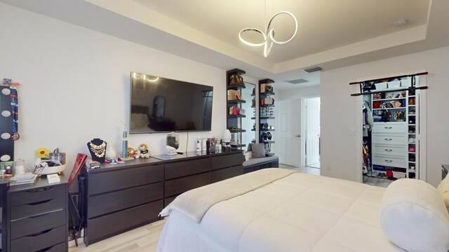 bedroom featuring light wood-type flooring and a raised ceiling