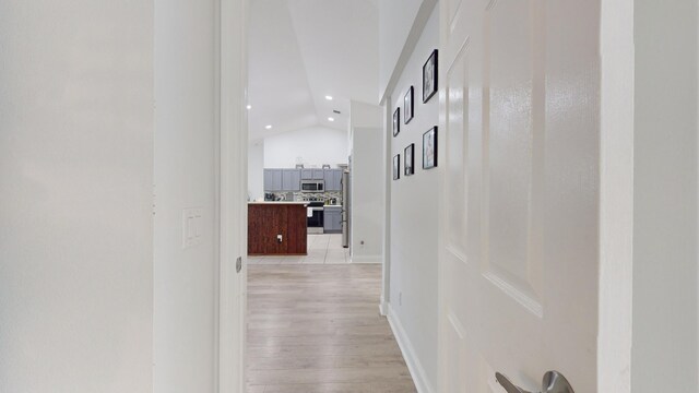 corridor with light hardwood / wood-style flooring and lofted ceiling