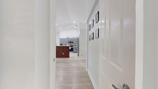 hallway with lofted ceiling, light wood-type flooring, baseboards, and recessed lighting