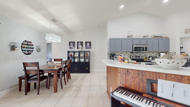 kitchen with decorative light fixtures, light tile patterned floors, stainless steel appliances, kitchen peninsula, and backsplash