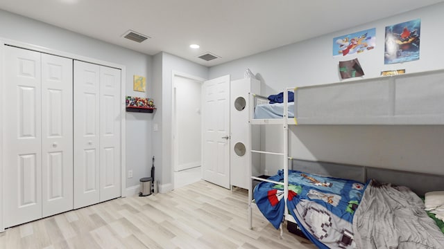 bedroom featuring light wood-type flooring, a closet, and visible vents