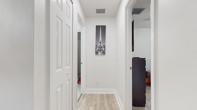 corridor featuring light wood-type flooring, visible vents, and baseboards