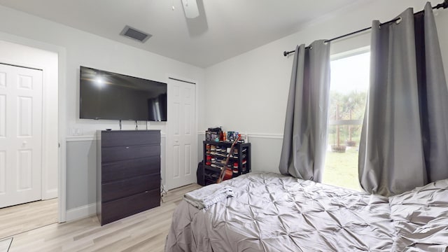 bedroom featuring baseboards, light wood-type flooring, visible vents, and a ceiling fan