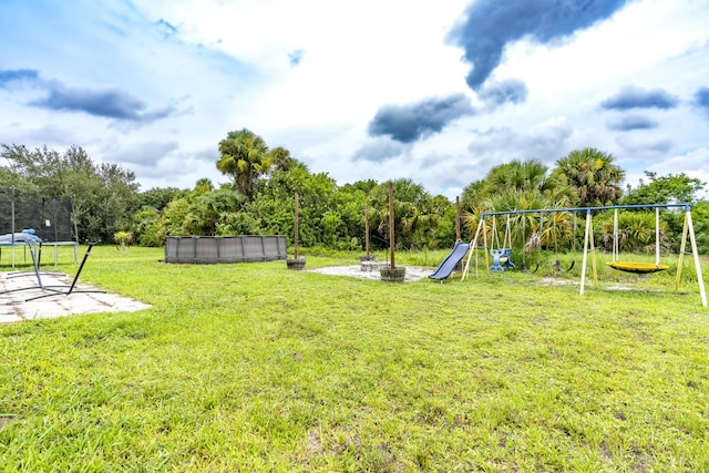 view of play area with a trampoline, an outdoor fire pit, an outdoor pool, and a lawn