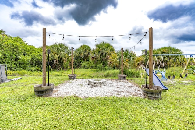 view of jungle gym featuring a yard and an outdoor fire pit