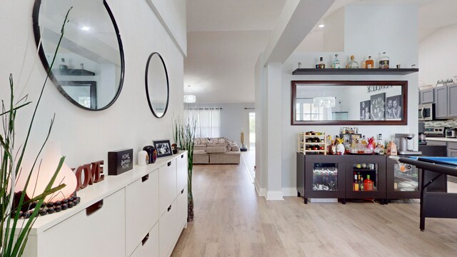 bar with light wood-type flooring and white cabinets