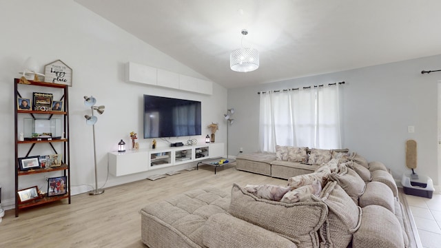 living area featuring lofted ceiling, light wood finished floors, and baseboards