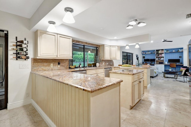 kitchen featuring cream cabinetry, dishwasher, light stone counters, and kitchen peninsula