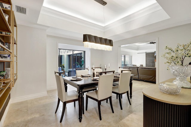 dining area featuring crown molding, a barn door, a raised ceiling, and light tile patterned flooring