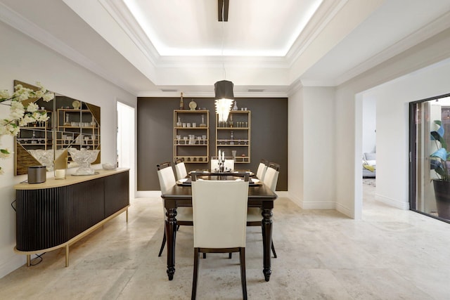 dining space with ornamental molding and a raised ceiling