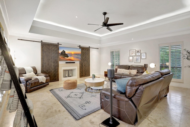 living room featuring ceiling fan, crown molding, a barn door, and a raised ceiling