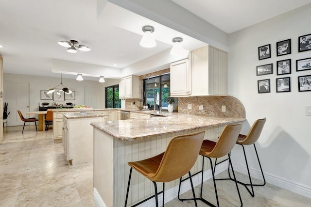 kitchen with tasteful backsplash, decorative light fixtures, a kitchen breakfast bar, and kitchen peninsula