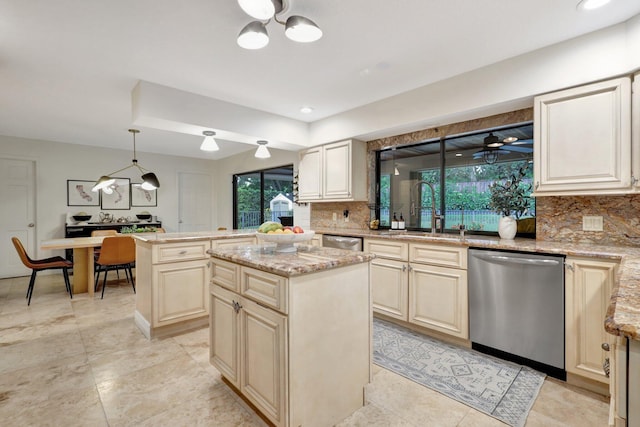 kitchen with sink, hanging light fixtures, a center island, stainless steel dishwasher, and light stone countertops