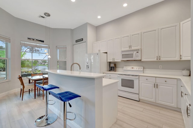 kitchen featuring pendant lighting, white appliances, white cabinets, and a kitchen island