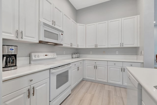 kitchen with white appliances, white cabinets, and light hardwood / wood-style floors