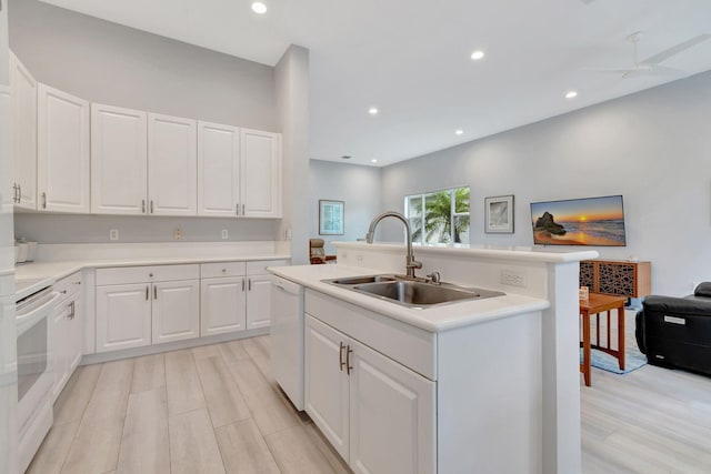 kitchen featuring white cabinets, dishwasher, sink, an island with sink, and stove