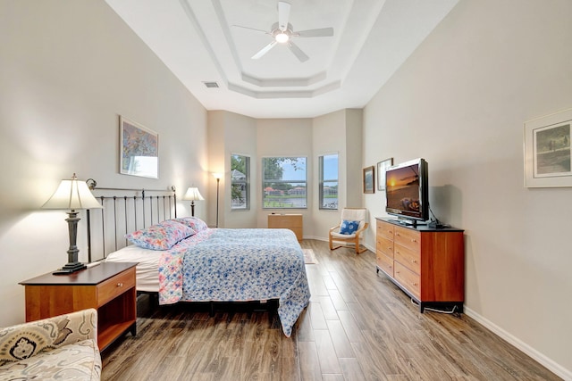 bedroom with a tray ceiling, hardwood / wood-style flooring, and ceiling fan