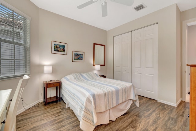 bedroom with dark wood-type flooring, ceiling fan, and a closet